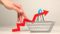 hand touching arrow on supermarket basket to signify inflation